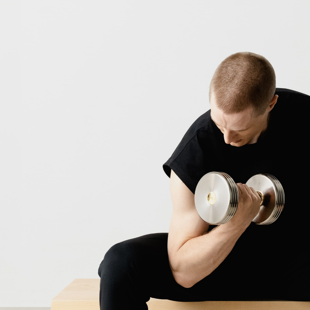 User doing muscle training with Kenko dumbbell featuring wooden handle design.