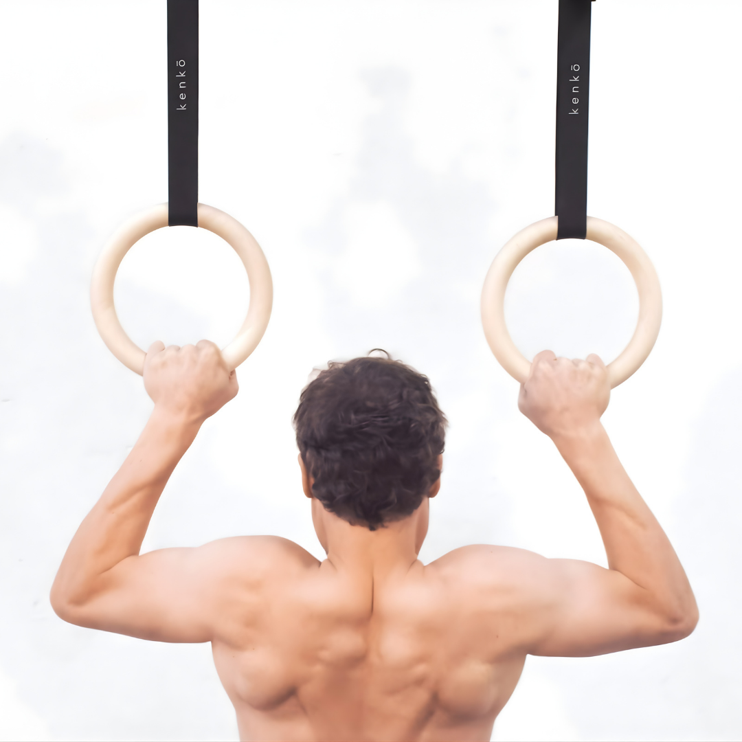 Maple wood gym rings showing a pale, natural grain pattern.