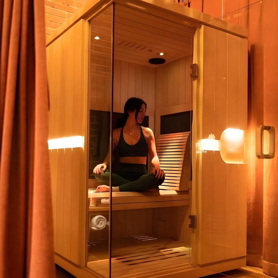Person relaxing inside infrared sauna with integrated red light therapy for detox and recovery.