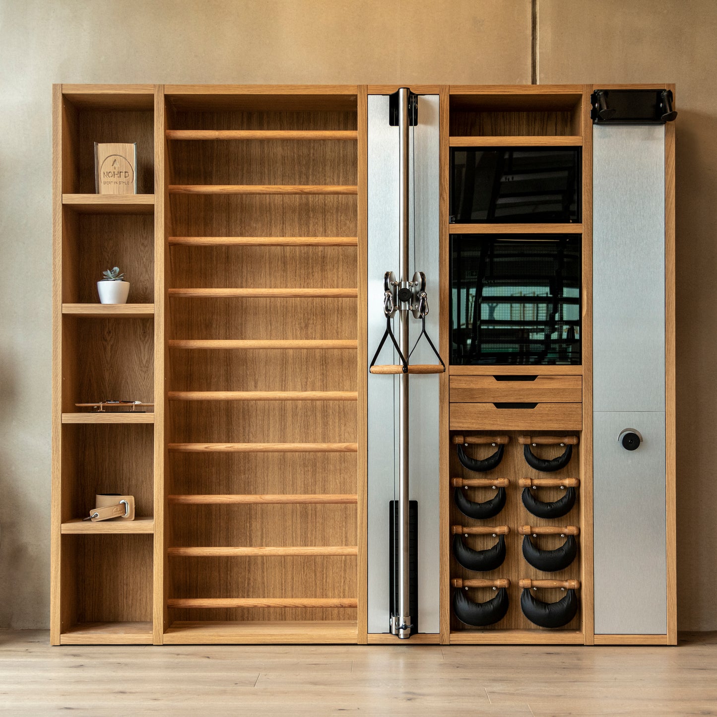 A luxurious gym equipment placed in a private gym, featuring cable machine, cross country ski trainer, four pairs of swing weights, wall bar, touchscreen tablet and shelving, all in walnut wood finish. NOHRD Wall - The Modular Solution