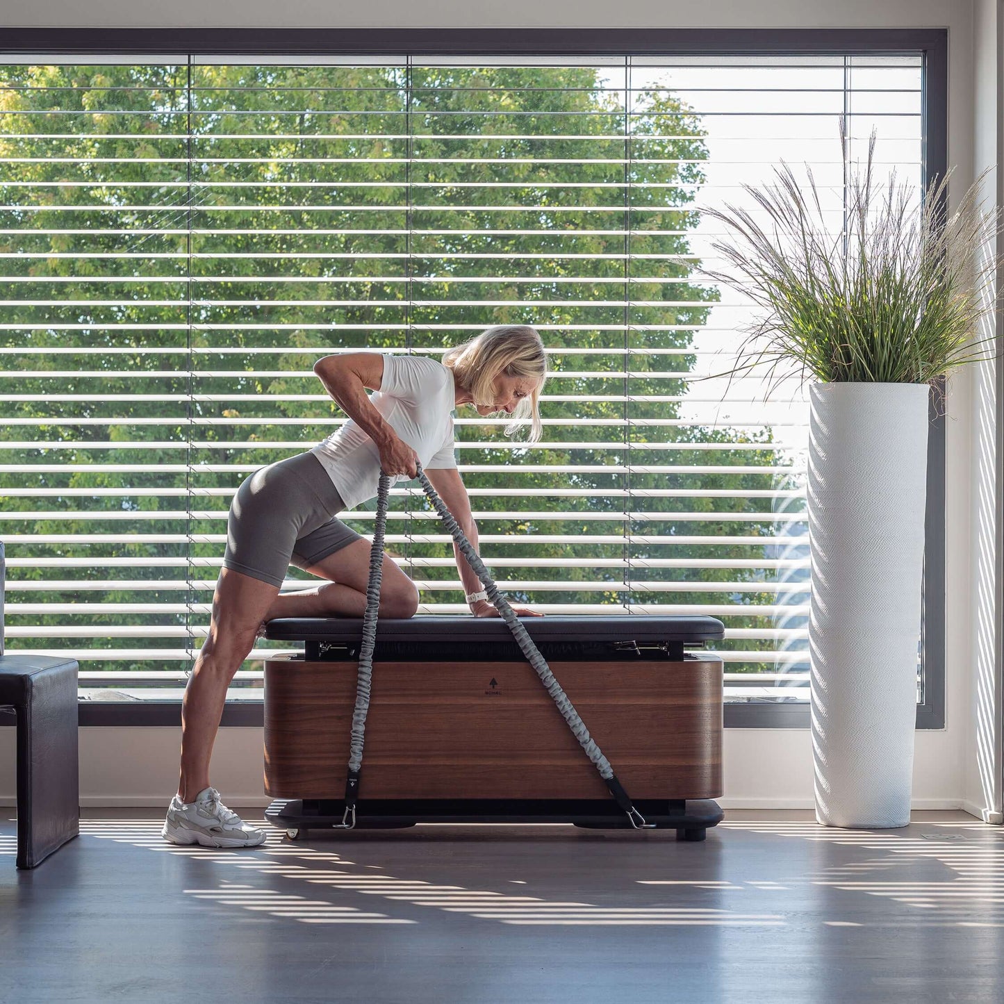 A fitness model doing exercise with the resistance tubes from the all in one fitness box in a home gym. Nohrd Stepbox