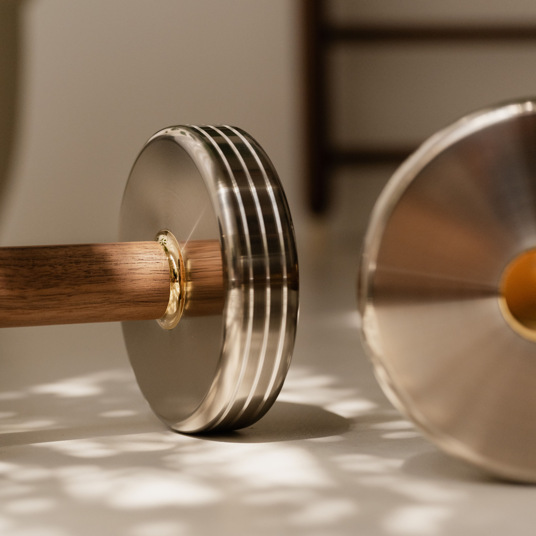 Close-up of walnut handle with polished brass accent on stainless steel dumbbell.