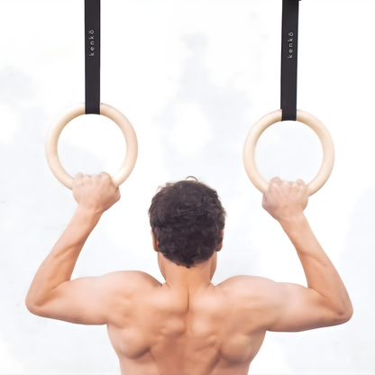 Maple wood gym rings showing a pale, natural grain pattern.