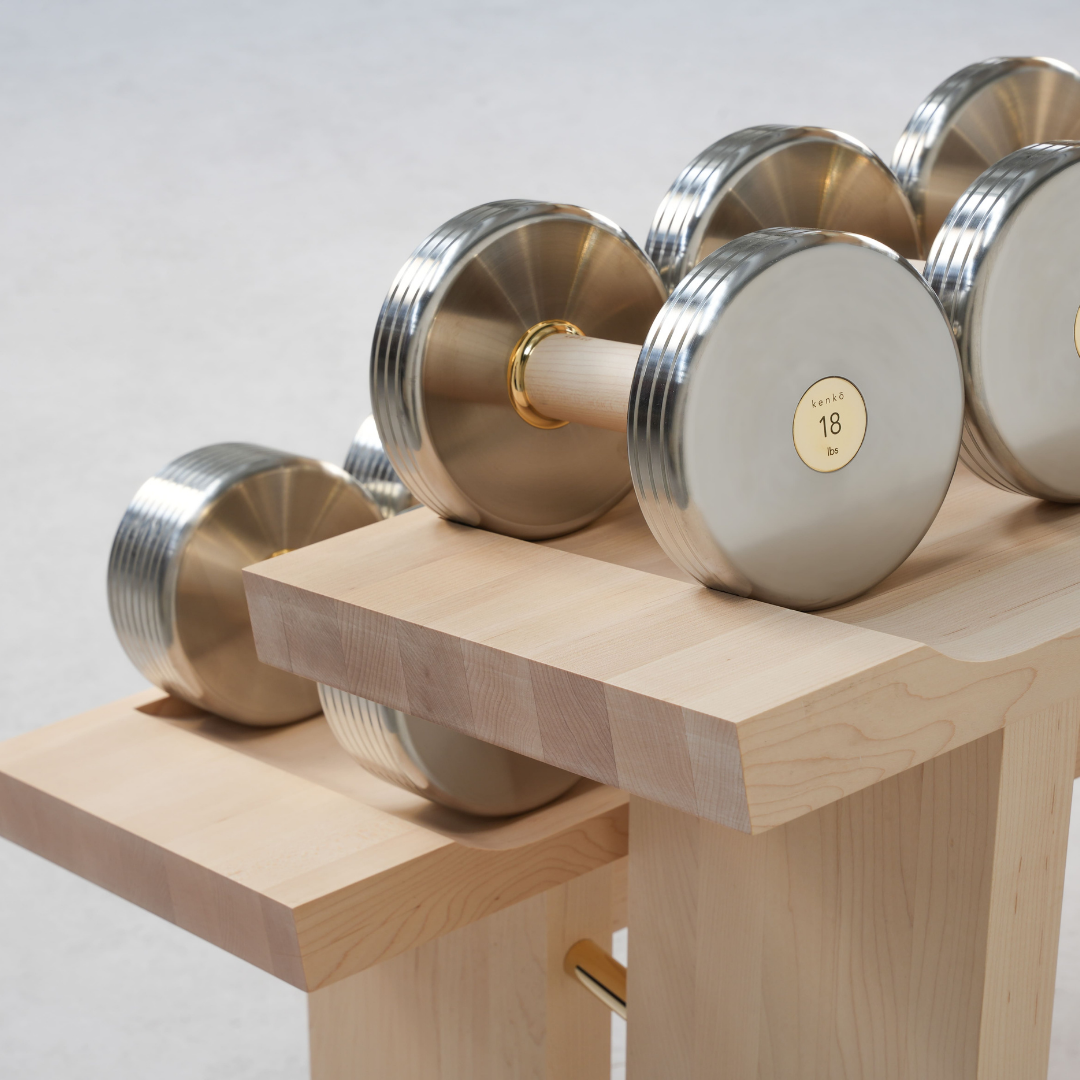 Close-up of walnut frame with polished brass detail on Cascada dumbbell rack.