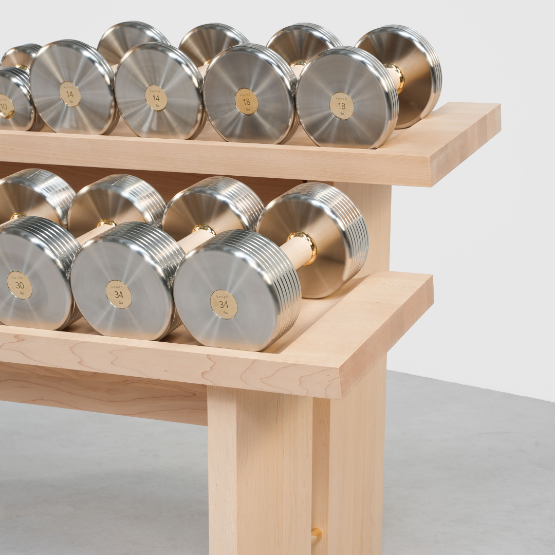 Close-up of walnut frame with polished brass detail on Cascada dumbbell rack.