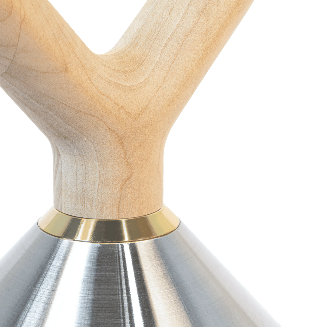 Close-up of maple handle with brass accent on polished stainless steel kettlebell.