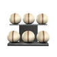 Six beige leather medicine balls with brown accent leather, arranged on two shelves made of black ash wood. PENT. MOXA Set Ultimate - Set of 6 Medicine Balls on Horizontal Wooden Stand