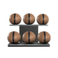 Six brown leather medicine balls with black accent leather, arranged on two shelves made of black ash wood. PENT. MOXA Set Ultimate - Set of 6 Medicine Balls on Horizontal Wooden Stand