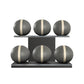 Six grey leather medicine balls with white accent leather, arranged on two shelves made of black ash wood. PENT. MOXA Set Ultimate - Set of 6 Medicine Balls on Horizontal Wooden Stand