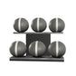 Six grey leather medicine balls with white accent leather, arranged on two shelves made of black ash wood. PENT. MOXA Set Ultimate - Set of 6 Medicine Balls on Horizontal Wooden Stand