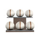 Six white leather medicine balls with brown accent leather, arranged on two shelves made of natural walnut wood. PENT. MOXA Set Ultimate - Set of 6 Medicine Balls on Horizontal Wooden Stand
