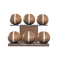 Six brown leather medicine balls with beige accent leather, arranged on two shelves made of natural walnut wood. PENT. MOXA Set Ultimate - Set of 6 Medicine Balls on Horizontal Wooden Stand