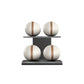 Four white leather medicine balls with brown accent leather, arranged on two shelves made of black ash wood. PENT. MOXA Power - Set of 4 Medicine Balls on Horizontal Wooden Stand