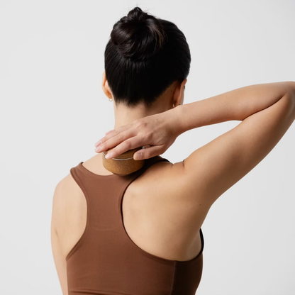 Person using a kenko massage ball on their neck and shoulders .