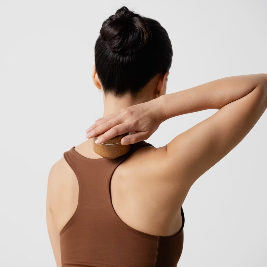 Person using a kenko massage ball on their neck and shoulders .