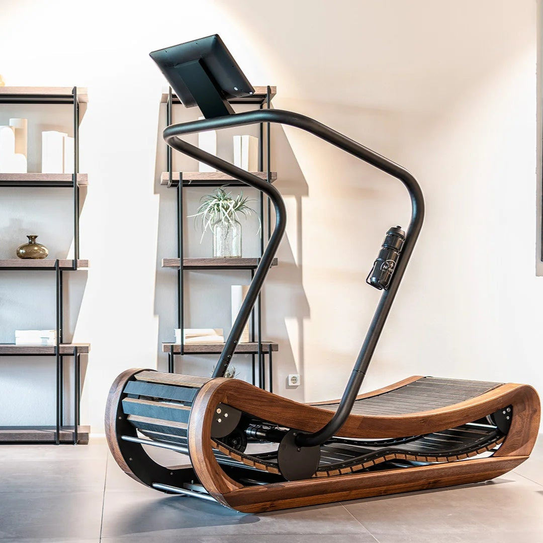 A premium gym equipment in a home gym, curved manual treadmill made of solid hardwood. Curved frame design in walnut wood finish. NOHRD Sprintbok V2 - Curved Manual Treadmill