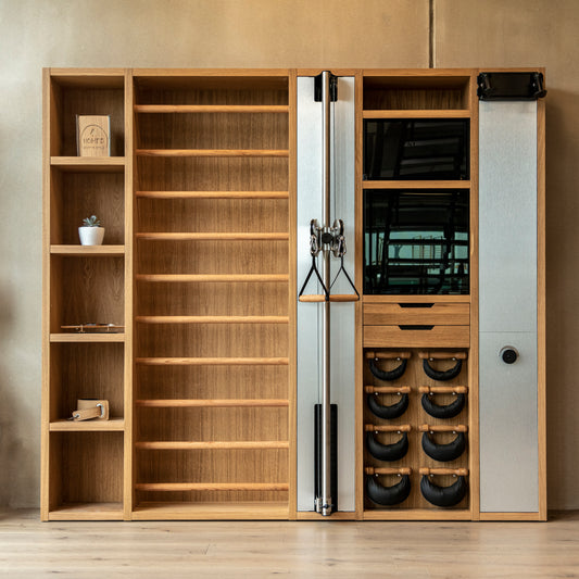 A luxurious gym equipment placed in a private gym, featuring cable machine, cross country ski trainer, four pairs of swing weights, wall bar, touchscreen tablet and shelving, all in walnut wood finish. NOHRD Wall - The Modular Solution