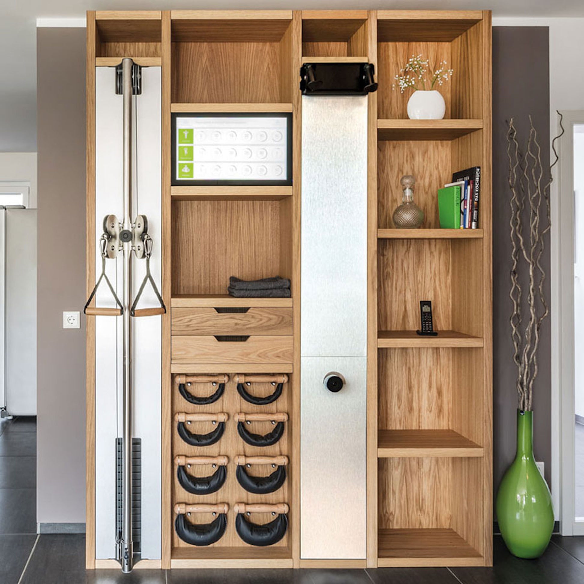 A luxurious gym equipment placed in a fitness space, featuring cable machine, cross country ski trainer, four pairs of swing weights, wall bar, touchscreen tablet and shelving, all in walnut wood finish. NOHRD Wall - The Modular Solution